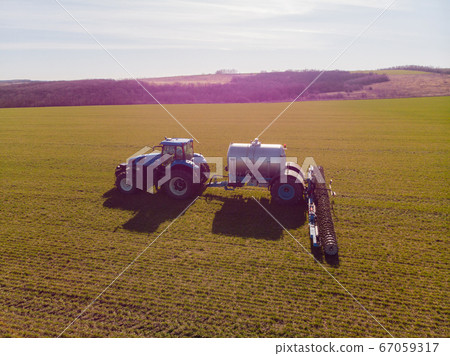 The introduction liquid mineral fertilizers into soil with tractor winter wheat 67059317