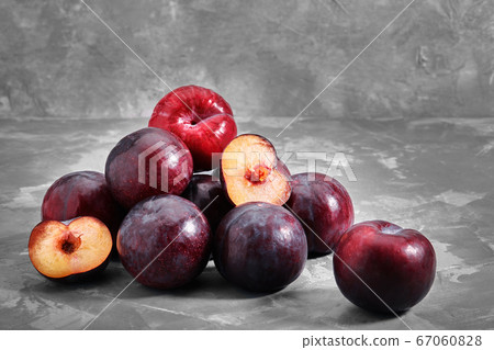 Ripe blue plums lie on a concrete stone background. Natural fruit background with place for text. Copy space. Autumn harvest background. 67060828