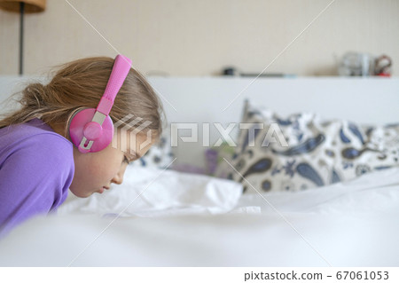 Girl in pink headphones with tablet device Girl in pink headphones with tablet device 67061053