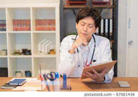 Young male doctor thinking in the examination room Young male doctor thinking in the examination room 67061436
