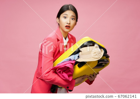 Surprised traveler holds in her hands a suitcase with clothes Surprised traveler holds in her hands a suitcase with clothes 67062141