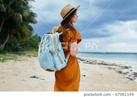 A traveler wearing a hat and with a backpack on his back near the ocean A traveler wearing a hat and with a backpack on his back near the ocean 67062149