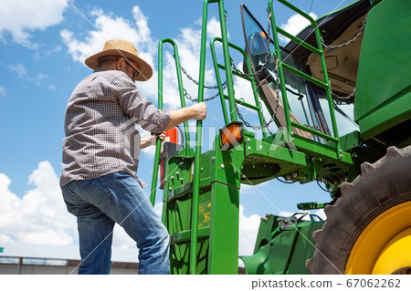 A farmer with a tractor, combine at a field in sunlight. Confident, bright colors A farmer with a tractor, combine at a field in sunlight. Confident, bright colors 67062262