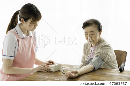 Caregiver measuring blood pressure of senior 67063787
