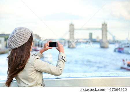 London woman tourist taking photo on Tower Bridge 67064310