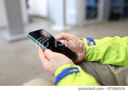 Close-up male hands in jacket hold smartphone 67066026