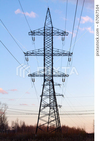 High voltage power lines in the middle of a field at sunset. Industrialization. Electrification. Power supply. High voltage power lines in the middle of a field at sunset. Industrialization. Electrification. Power supply. 67067584
