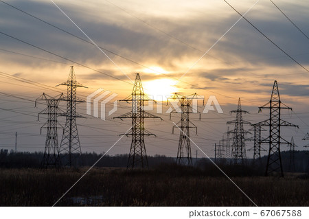 High voltage power lines in the middle of a field at sunset. Industrialization. Electrification. Power supply. High voltage power lines in the middle of a field at sunset. Industrialization. Electrification. Power supply. 67067588