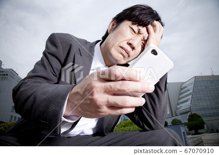 Business man worried about seeing a smartphone 67070910