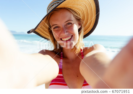 Portrait of woman wearing hat smiling on the beach Portrait of woman wearing hat smiling on the beach 67071951