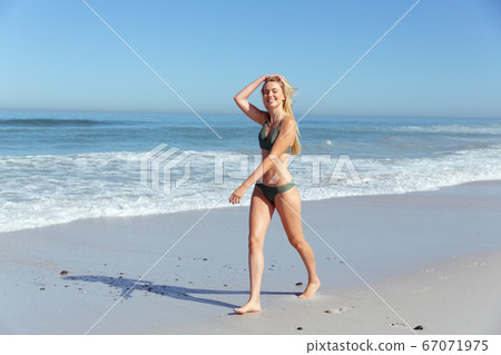 Beautiful woman walking on the beach Beautiful woman walking on the beach 67071975