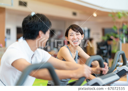 Couple doing exercise bikes at the gym Couple doing exercise bikes at the gym 67072535