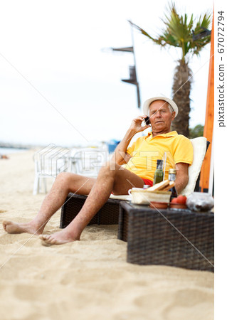 Cheerful mature man sitting and speaking phone 67072794