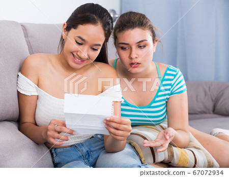 Young girl reading love letter with friend Young girl reading love letter with friend 67072934