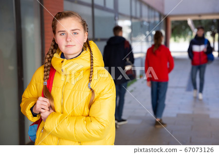 Positive teen girl in yellow jacket walks down the street Positive teen girl in yellow jacket walks down the street 67073126