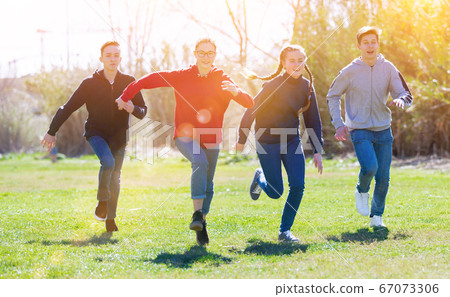 Cheerful teens running on green lawn 67073306