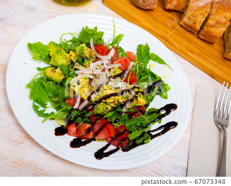 Salad with avocado, tomato, green arugula and onion in balsamic 67073348