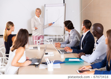 Woman reading out report to colleagues 67073418