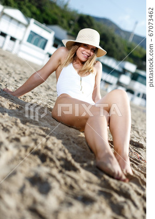 Female in swimsuit taking sunbath at sand at sea shore on sunny day Female in swimsuit taking sunbath at sand at sea shore on sunny day 67073462