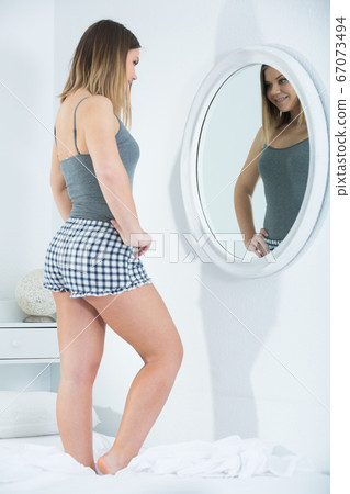 Young female in pygama, using mirror in bedroom 67073494