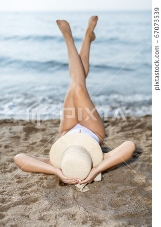 Closeup of young woman in swimsuit and hat taking sunbath Closeup of young woman in swimsuit and hat taking sunbath 67073539