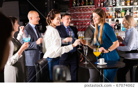 Young attractive women with cocktails having fun with workmates on office party at nightclub Young attractive women with cocktails having fun with workmates on office party at nightclub 67074002