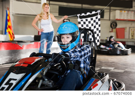 woman driving sport car and woman with race flag on\
background