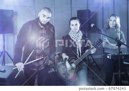 Three bandmates posing together with musical instruments in rehe Three bandmates posing together with musical instruments in rehe 67074243