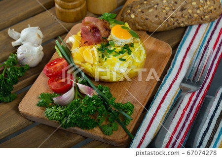 Baked potato stuffed with herbs, egg, bacon 67074278