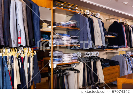 Fashion modern men clothes displayed on shelves and hanger racks in clothing store Fashion modern men clothes displayed on shelves and hanger racks in clothing store 67074342