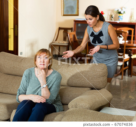 Offended elderly mother with adult daughter reprimanding her 67074836