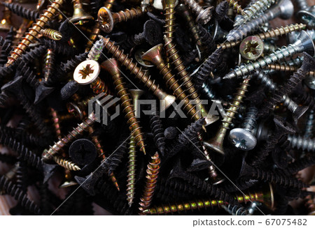 Bunch of different screws on a wooden surface Bunch of different screws on a wooden surface 67075482