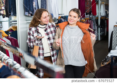Women trying coat in clothing boutique 67075527