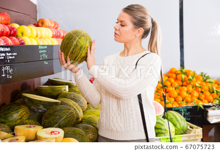 Smiling female customer choosing melon and fruits on the market Smiling female customer choosing melon and fruits on the market 67075723