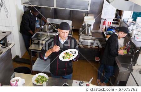 Staff of restaurant with chef working Staff of restaurant with chef working 67075762