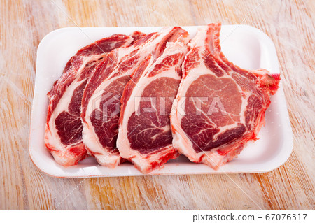 Plastic tray with raw pork chops on bone Plastic tray with raw pork chops on bone 67076317