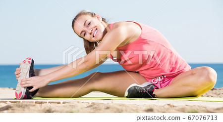 Girl workout at sea beach on sunny day Girl workout at sea beach on sunny day 67076713