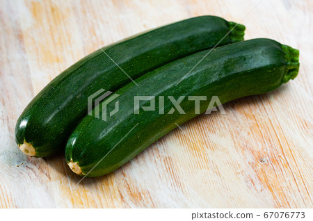 Raw green zucchini on wooden surface in kitchen Raw green zucchini on wooden surface in kitchen 67076773