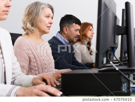 Side view of coworkers during daily work at computers in office Side view of coworkers during daily work at computers in office 67076910