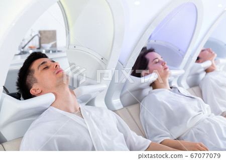 Clients of beauty salon relaxing on massaging chairs 67077079