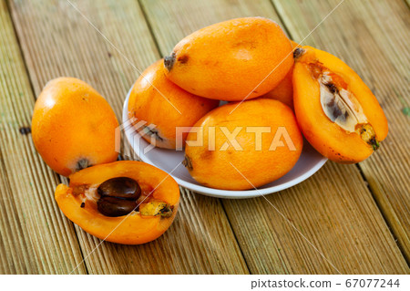 Whole and halved Japanese medlar 67077244