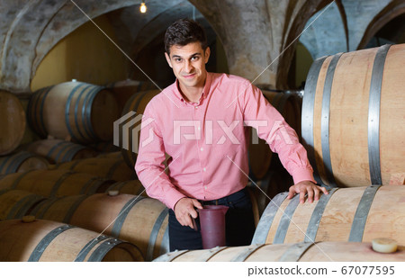 Male customer tasting red wine from wooden barrels 67077595