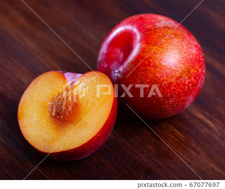 Whole and halved ripe red plums Whole and halved ripe red plums 67077697