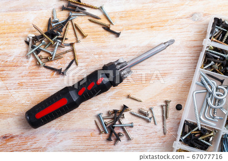 Screwdriver and screws on wooden table 67077716