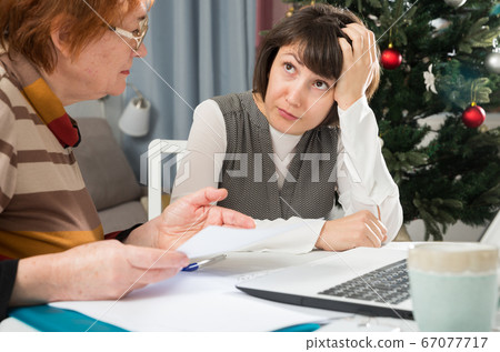 Sad young female and mother with financial documents 67077717
