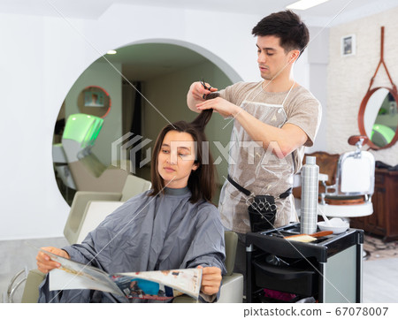 Stylist doing haircut for woman in salon Stylist doing haircut for woman in salon 67078007