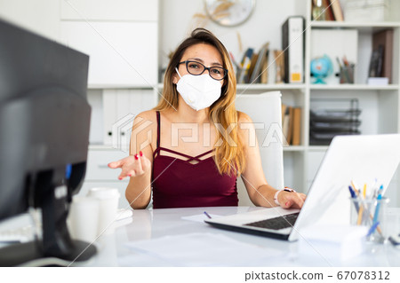 Young colombian woman in mask working with laptop Young colombian woman in mask working with laptop 67078312