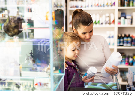 Woman with daughter searching aquarium supplies in shop Woman with daughter searching aquarium supplies in shop 67078350
