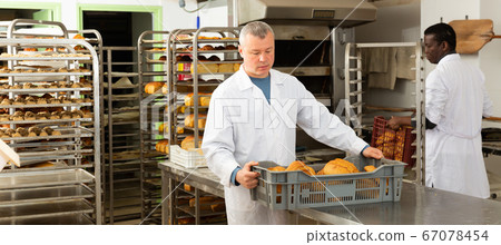 Baker carrying fresh bread in box 67078454