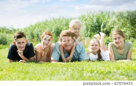 Friendly man and woman with kids lying in park Friendly man and woman with kids lying in park 67078455